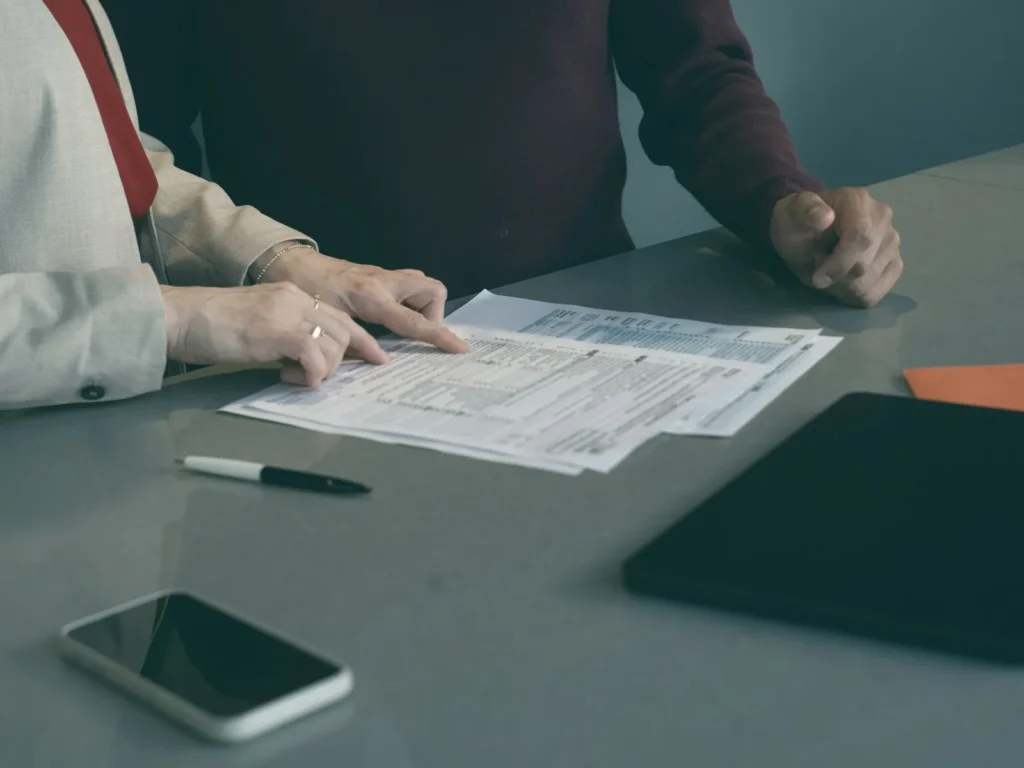 Dos personas revisando documentos sobre una mesa de reunión